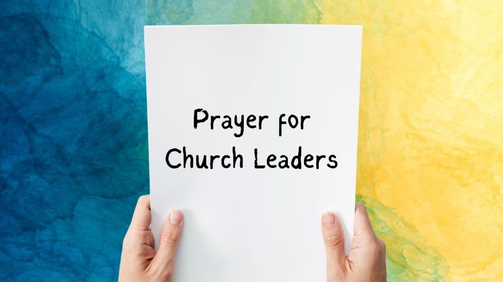 prayer for church leaders written on a piece of paper, being held by two hands, on a multicolored background