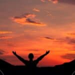2 - person praying with hands outstretched in front of a sunset - prayer points for spiritual growth and character