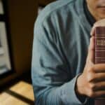 2 - man praying holding Bible - Bible verses about God's power