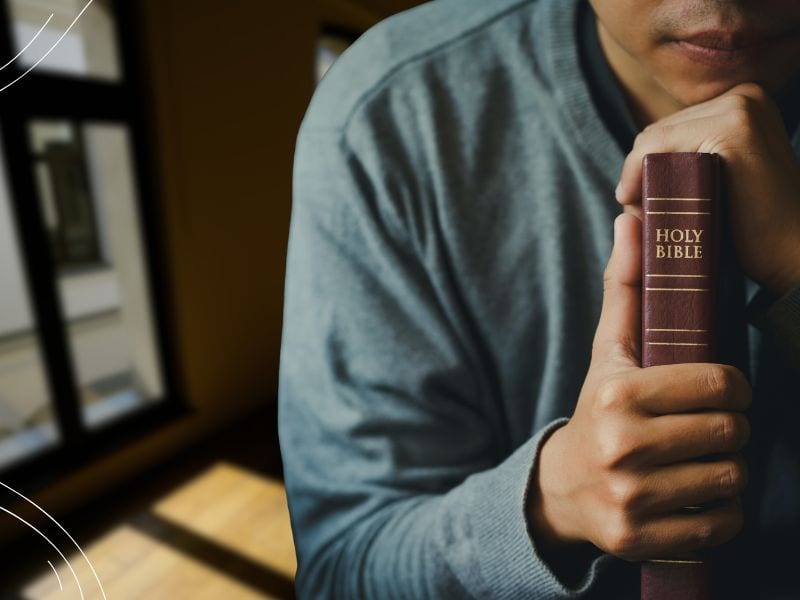 2 - man praying holding Bible - Bible verses about God's power