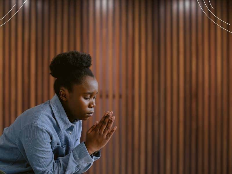 woman praying in a room with a wood wall - nurturing a thankful heart (2)