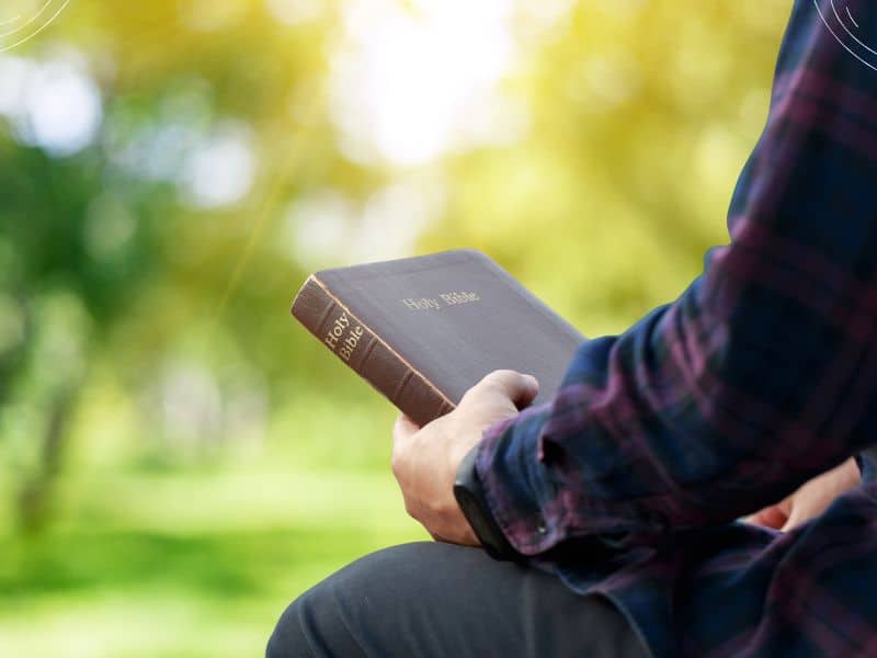 Bible reading plans - man holding Bible while sitting outside